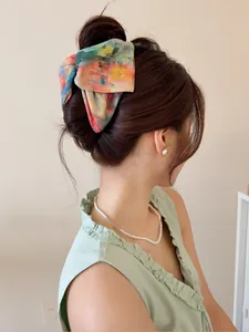 Pince à cheveux tie-dye portée sur une coiffure mi-haute pour un style élégant