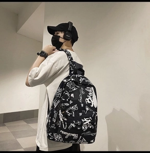 Detail of street style backpack featuring white graffiti print on black canvas material