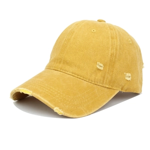 Detailed macro view of mustard yellow washed cotton baseball cap with distressed rip effects
