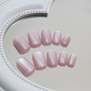 Pink cat eye short press-on nails set with subtle shimmer on a heart-shaped mirror