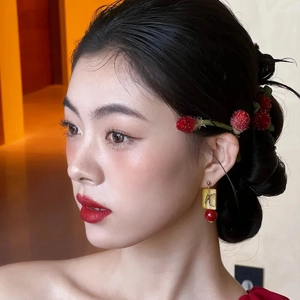 Dettaglio di orecchini quadrati vintage con perline rosse su modella asiatica