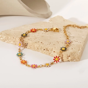 Detalle de pulsera de acero de titanio oro 18K con colgantes de margaritas de colores