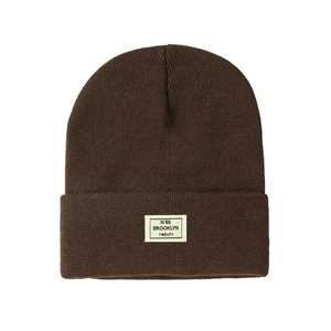 Detailed view of the woven Brooklyn patch on a dark brown ribbed knit beanie hat