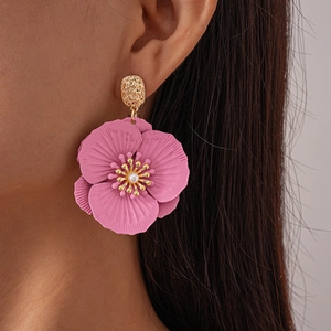 Close-up of pink flower petal earring with pearl center on a model's ear