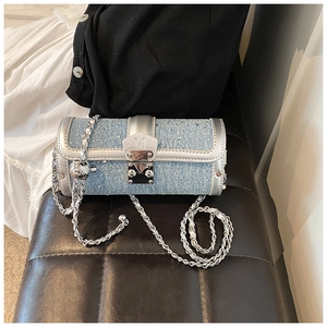 Detail of light blue denim cylinder bag with rhinestones and silver chain strap