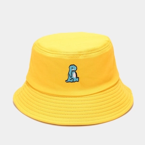 Detail of cute blue dinosaur embroidery on yellow cotton canvas bucket hat fabric