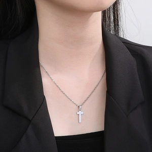 Close-up of minimalist silver stainless steel cross pendant necklace on male model wearing black suit