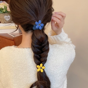 Détail de chouchous fleurs floqués bleu et jaune avec strass sur une tresse en épi de blé