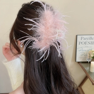 Detail of pink feather hair claw clip on dark hair with elegant minimalist background