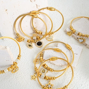 Gold twisted wire bangles with various charms including evil eye and stars on white stone
