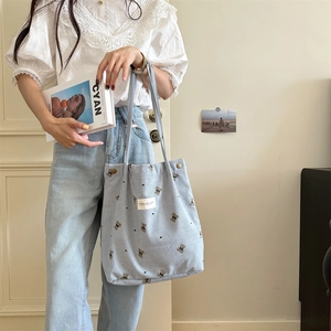 Detail of light blue corduroy shoulder bag with vintage bear print and textile label