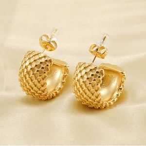 Détail macro de boucles d'oreilles en C en acier doré 18K avec surface perlée texturée