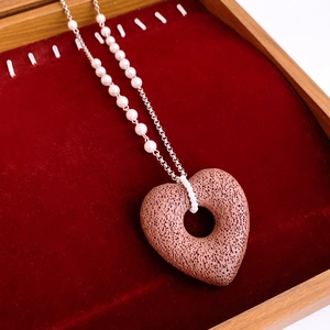 Detail of heart volcanic stone pendant on silver chain with small white beads