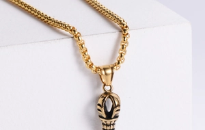 Detail of vintage 18K gold plated totem pillar pendant with classic box chain necklace