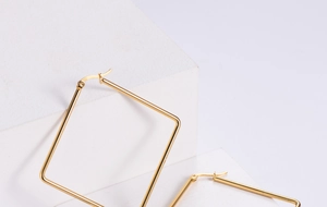 Close-up of gold square hoop earrings with polished finish on geometric pedestals