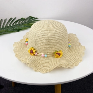 Detail of a kids straw sun hat featuring sunflower beads and a scalloped wavy brim