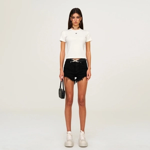 Minimalistisches weißes T-Shirt mit Kreuz-Logo und Denim-Shorts an Model im Studio