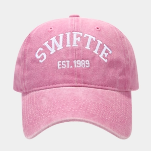Close-up of Swiftie Est. 1989 white embroidery on a pink washed cotton baseball cap