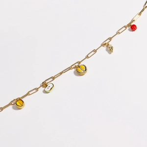 Detailed shot of golden charm bracelet with colorful enamel fruit pendants on white background
