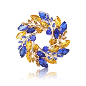 Elegant wheat wreath brooch with blue and yellow crystals on a gold setting