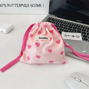 Detail of pink drawstring canvas pouch with heart patterns and woven brand label