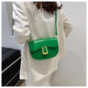 Detail of green PU leather saddle bag with gold D-ring hardware on white blazer