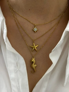 Gros plan de colliers dorés superposés avec pendentifs étoile de mer et hippocampe
