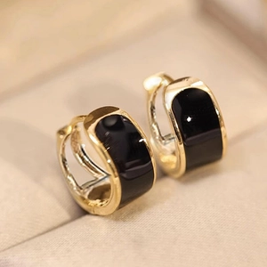 Macro detail of minimalist gold U-shaped hoop earrings with black enamel finish