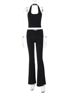Dettaglio di un set nero a due pezzi con crop top all'americana e pantaloni svasati a vita alta