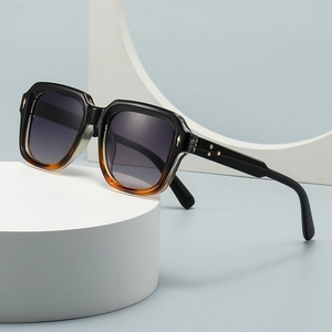 Oversized square gradient sunglasses with gold star rivets on a modern white pedestal