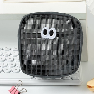 Close-up of a grey mesh pouch with funny big eyes embroidery on a white keyboard