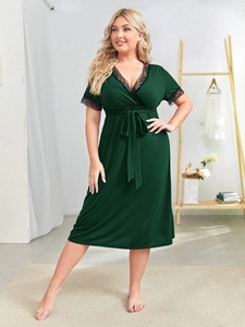 Close-up of deep green V-neck dress featuring delicate black lace trim and belt detail