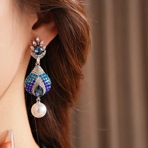 Primo piano di orecchini vintage con perle a goccia e strass blu su modella