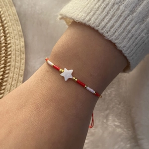 Handmade beaded bracelet with shell star charm and red white gold beads on wrist