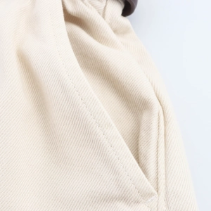 Dettaglio ravvicinato della trama in twill di cotone beige e cuciture sui pantaloncini
