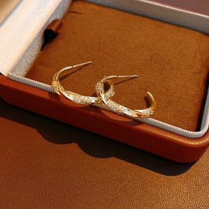 Macro view of 18K gold plated twisted C-shape hoop earrings with micro-set zircon stones