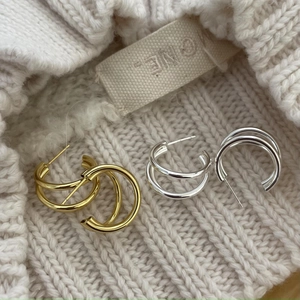 Close-up of gold and silver layered hoop earrings on white knitted fabric background