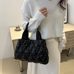 Chic black quilted puffer tote bag for women featuring padded straps and minimalist design