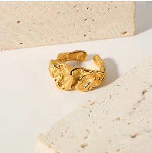 Close-up of golden irregular lava texture ring placed between natural beige stones