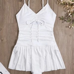 White eyelet fabric one-piece swimsuit with ruffled hem on wooden background