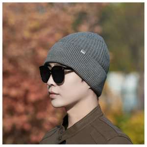 Outdoor shot of a grey ribbed knit beanie for men with a metallic logo detail