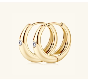 Close-up of gold hoop earrings featuring polished finish and single diamond accent