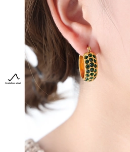 Detail of gold plated stainless steel C-hoop earring with green pavé set crystals