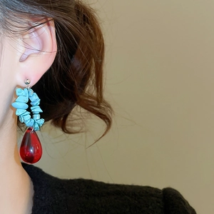 Detail of ethnic earrings with turquoise beads and deep red teardrop crystal pendant