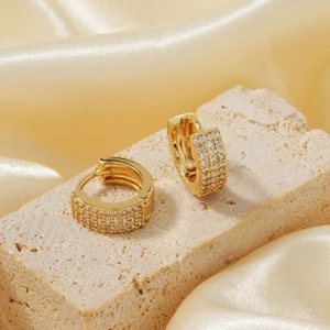 Close-up of golden hoop earrings with triple-row micro-pave white zircon stones