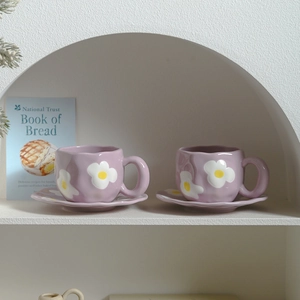 Detailed close-up of purple ceramic coffee mugs with white flower patterns and matching saucers