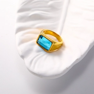 Minimalist 18k gold plated titanium ring with blue rectangular gemstone on white leaf