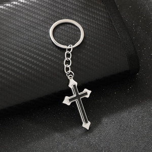 Macro shot of silver metal gothic cross keychain with black inlay on dark textured wallet