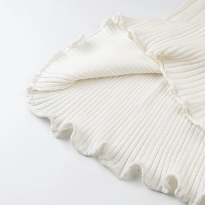 Close-up detail of white ribbed knit fabric texture and elegant ruffled hem design