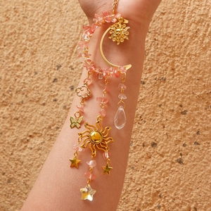 Detail of moon suncatcher with pink crystals, golden stars, and butterfly ornaments